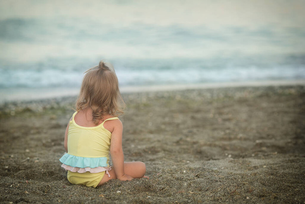 Κορίτσι με σύνδρομο Down κάθεται στην παραλία - Φωτογραφία, εικόνα