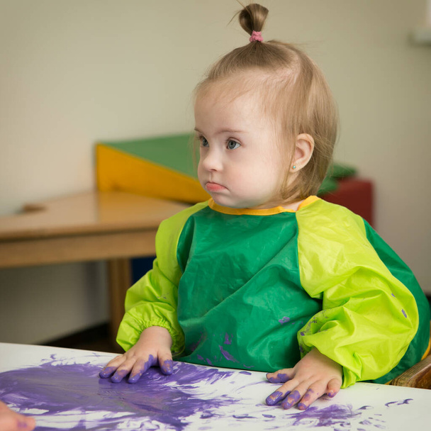 Dziewczyna z zespołem Downa rysuje palce farby - Zdjęcie, obraz