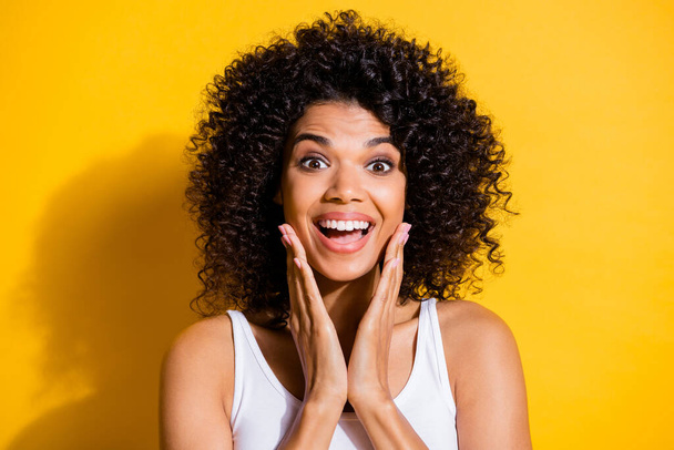 Photo of cheerful astonished dark skin lady arms on cheeks open mouth isolated on yellow color background - Zdjęcie, obraz