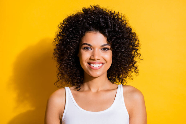 Photo of sweet pretty young dark skin woman dressed white tank-top smiling isolated yellow color background - Fotó, kép