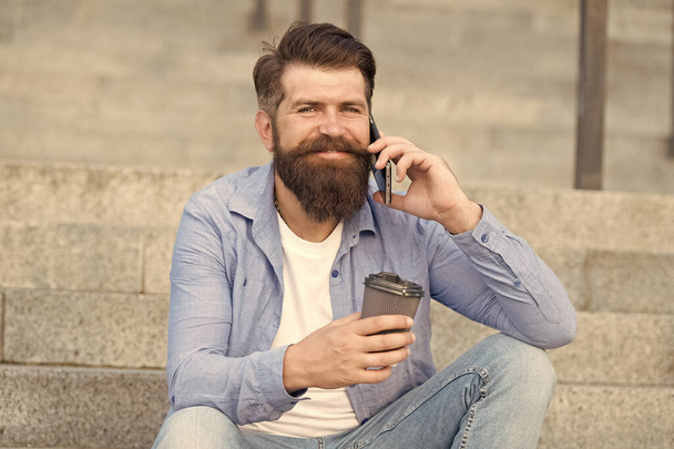 Small talk with someone. Happy hipster drink coffee talking on phone outdoors. Making phone call. Cell phone connection. New technology. Modern life. Mobile phone makes communication easier - Fotoğraf, Görsel