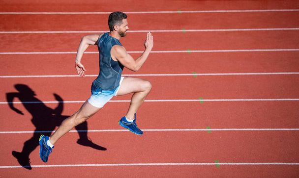 energetic athletic muscular man runner running on racetrack at outdoor stadium, hurry up - Foto, immagini