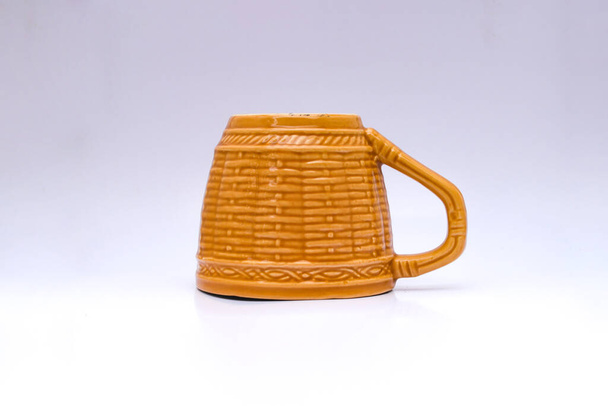Leere gelb-braune Tasse mit geflochtenem Bambusmotiv isoliert auf weißem Hintergrund - Foto, Bild