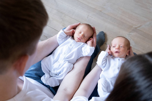Novorozená identická dvojčata na posteli, na rukou rodičů. Životní styl, emoce dětí. Kojenci s kopírovacím prostorem - Fotografie, Obrázek