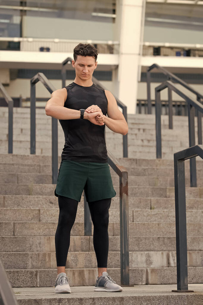 fitness and sport. Workout in gym. A man runs looking at his pulse outside with a smart watch. Athlete runner testing cardio on sport running smartwatch at outdoor jogging - Foto, Imagen
