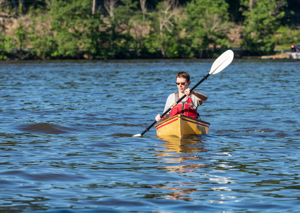 Male caucasian paddling a pack canoe with a kayak paddle on lake - Photo, Image