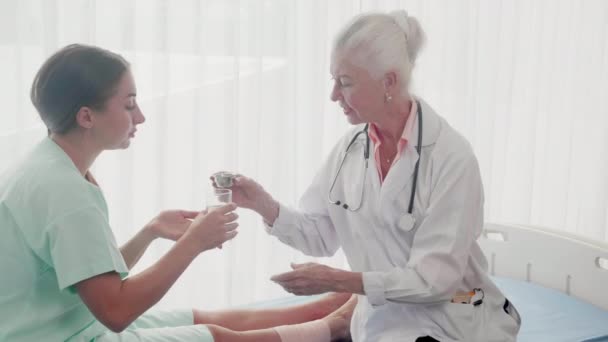 Lekarz starszy specjalista dający pigułki z pacjentem do leczenia w szpitalu, lekarz dający lek z kobietą do leczenia w klinice, dwie osoby, opieka zdrowotna i pomoc, koncepcja opieki medycznej i zdrowotnej. - Materiał filmowy, wideo