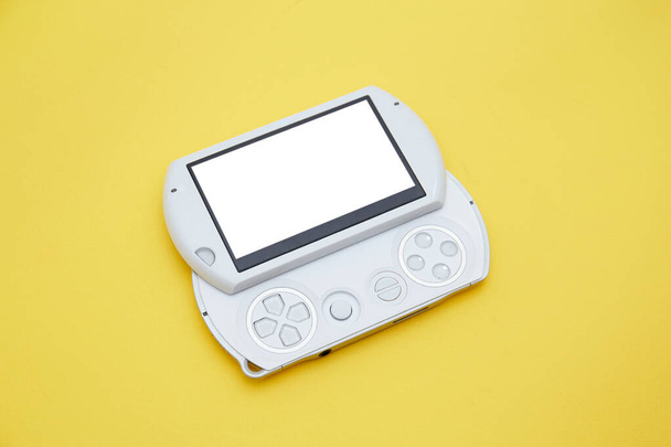 Bovenaanzicht van witte handheld spelcomputer met joystick geïsoleerd op geel  - Foto, afbeelding