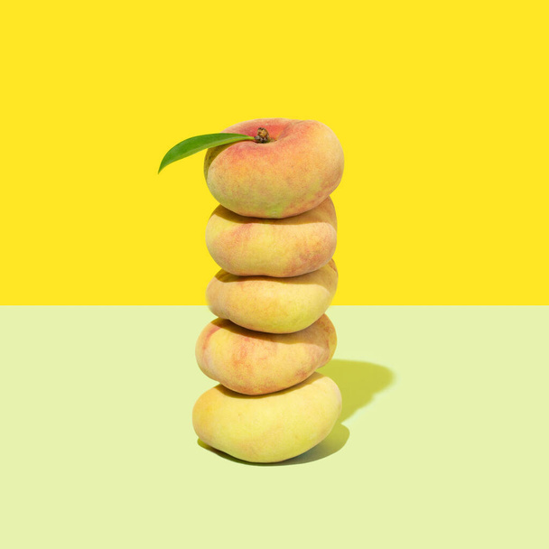 Свежие органические персики, сложенные друг на друге на зеленом дне и ярко-желтом фоне. - Фото, изображение