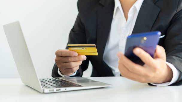 Una mujer joven paga con una tarjeta de crédito en línea mientras que hace una compra en línea en un ordenador portátil. Empresarios exitosos realizan transacciones utilizando la aplicación de banca móvil. - Foto, imagen