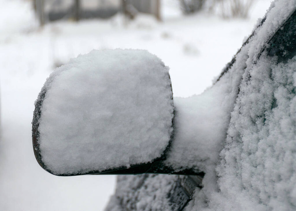 verse sneeuw bedekt de omgeving en de auto spiegel, sneeuw textuur op een metalen oppervlak, winter - Foto, afbeelding