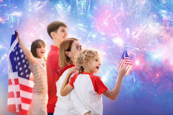 Amerykańska rodzina świętuje 4 lipca. Ludzie oglądają fajerwerki z okazji Dnia Niepodległości z flagą USA. Dumne dzieci z USA wiwatują i świętują. Dziecko z symbolem Ameryki. Święto narodowe. - Zdjęcie, obraz