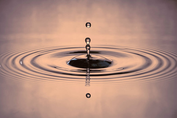 Wassertropfen plätschern in einem grau gefärbten Schuss Wasser, das tropft und Wasser reflektiert.. - Foto, Bild