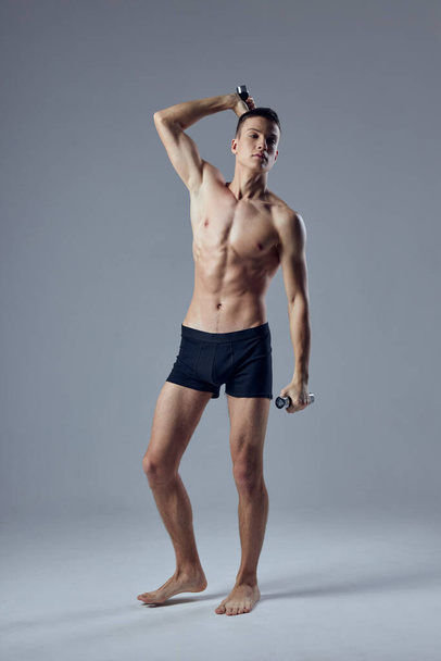 urheilullinen mies lihaksikas vartalo musta pikkuhousut käsipainot kädessä harjoitus harjoitukset - Valokuva, kuva