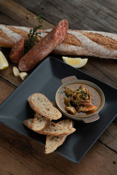 Gambas Pil Pil - Crevettes pétillantes au chili et à l'ail servies avec du pain sur le côté isolé sur une table rustique en bois - Photo, image