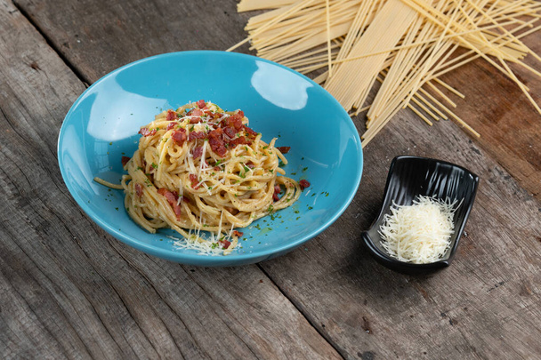 Plat de pâtes italien traditionnel, spaghetti carbonara au bacon, jaune, parmesan sur une assiette isolée sur une table en bois - Photo, image