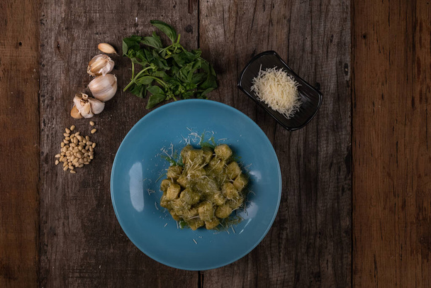 Top näkymä kotitekoinen gnocchi pesto kastike, parmesaani ja basilika eristetty puinen pöytä - Valokuva, kuva