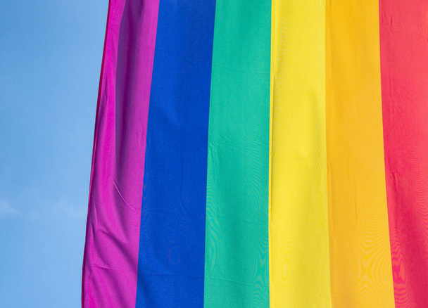 Rainbow flag in sunshine against blue sky - Foto, afbeelding