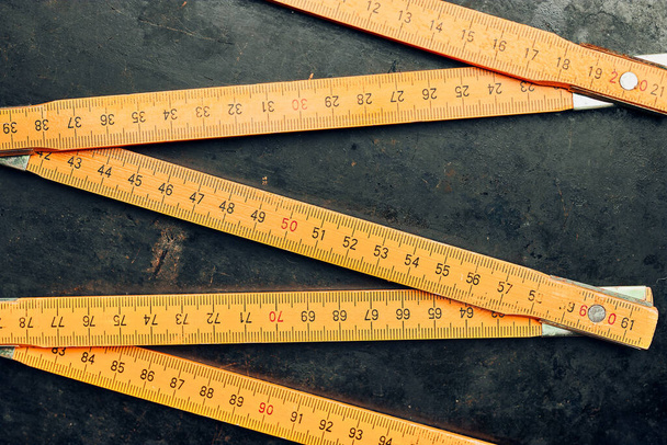 Wooden measure. Old ruler on metal surface. Measuring tool. Technical background with copy space - Foto, Imagem