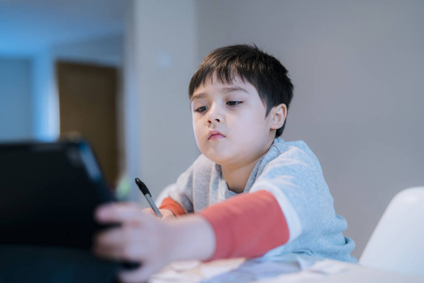 Hiteles portré az óvodás gyerekről, aki táblagépet használ a házi feladatához, Új normális élet gyermek fiú érintőpad otthoni tanuláshoz, E-learning vagy Vissza az iskolába koncepció - Fotó, kép