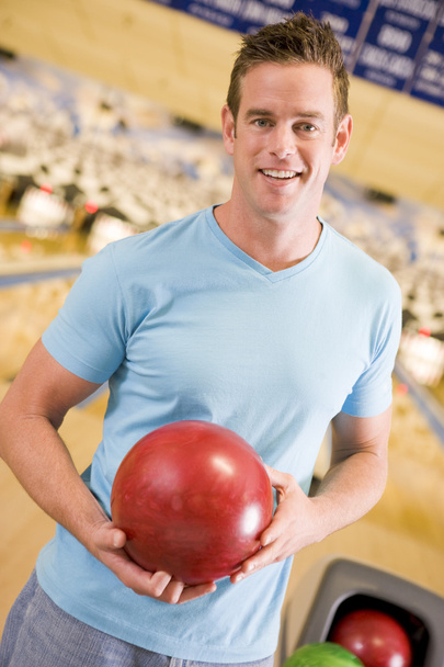 Young man holding a bowling ball in a bowling alley - Fotó, kép