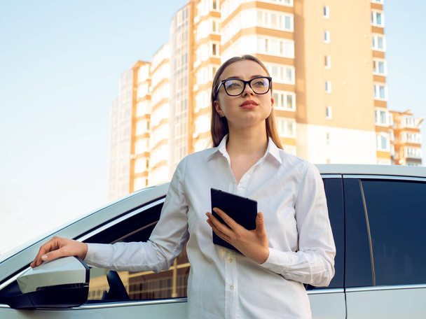 現代女性ビジネス女性とタブレットで彼女の手に彼女の車の近く.  - 写真・画像