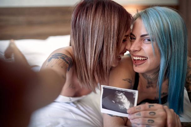 Joyful lgbt couple sharing a pregnancy test results together - Фото, изображение