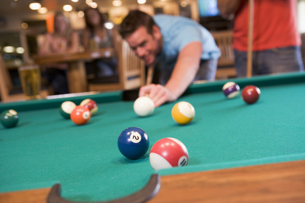 Young man playing pool in a bar (focus on pool table) - Photo, Image