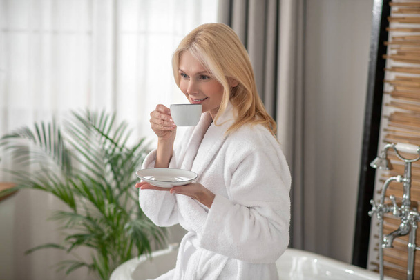 Good-looking blonde woman having tea and looking balanced - Фото, изображение