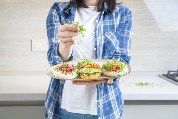 新鮮なマイクログリーンのもやしと野菜で作られた女の子の料理ビーガントースト - 写真・画像