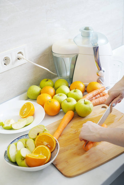 Preparing homemade fresh juice made with apples, oranges and carrots. - Foto, afbeelding