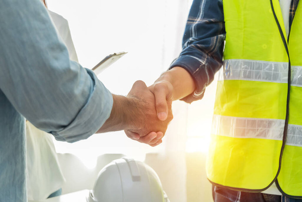 Contractor. construction worker team hands shaking after plan project contract on workplace desk in meeting room office at construction site, contractor, engineering, partnership, construction concept - Φωτογραφία, εικόνα