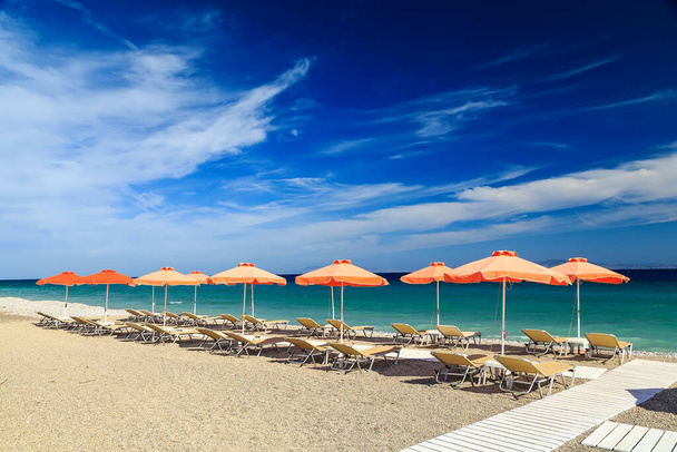 Білі дерев'яні проходи на пляжі, включаючи парасольки з палубними стільцями. Егейське море. Греція Родос. - Фото, зображення
