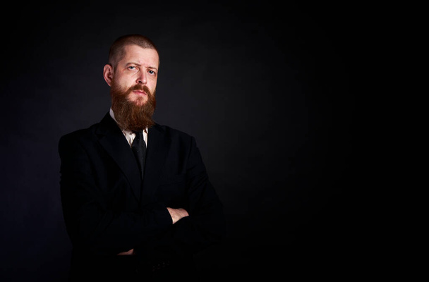 hombre de negocios con barba sobre fondo negro en traje negro - Foto, Imagen