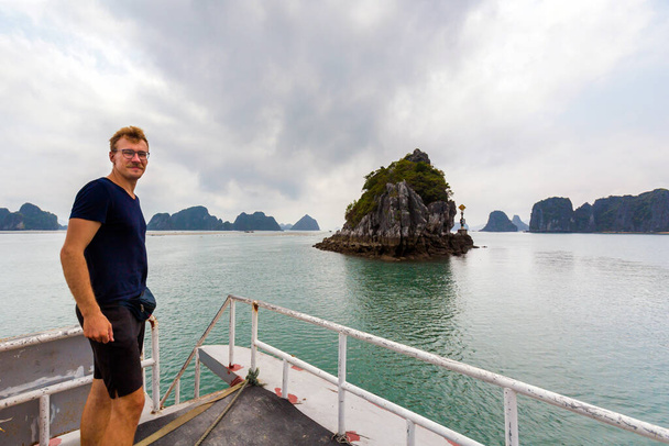 Prachtig landschap met jonge mannelijke toerist van Bai Tu Long Bay, genomen tijdens de cruise naar Quan Lan eiland, Vietnam. Landschapsfoto genomen in Zuidoost-Azië, Ha Long - Foto, afbeelding