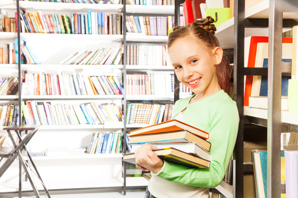 Schoolgirl   holds books in library - Zdjęcie, obraz