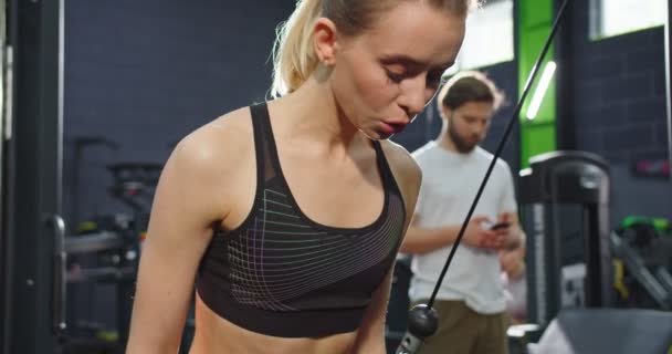 Portrait view of the strong healthy tired women doing push ups while training arms with trx fitness straps in the loft gym. Concept of the workout and healthy lifestyle - Video