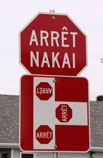 красный и белый знак стоп с текстом стоп на французском и местном родном канадском языке инну (arrt означает стоп, nakai означает стоп) - Фото, изображение