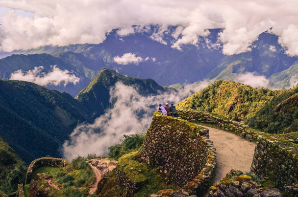 Wysoki kąt odległego widzenia trzech Backpacker męskich przyjaciół kontemplujących ogromną dolinę przed nimi na ruinach Phuyupatamarca. Szlak Inków do Machu Picchu w Peru. Ameryka Południowa - Zdjęcie, obraz