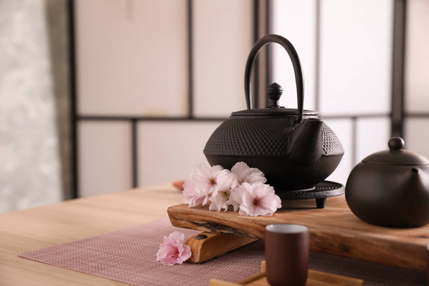 Beautiful traditional tea ceremony set and sakura flowers on wooden table. Space for text - Photo, image