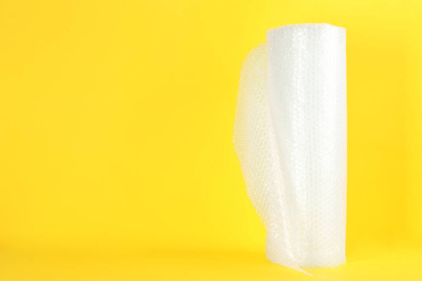 Bubble wrap roll on yellow background, space for text - Foto, Imagen