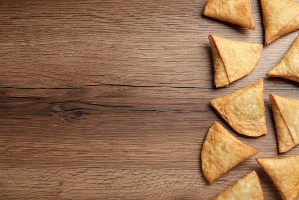 Fresh delicious crispy samosas on wooden table, flat lay. Space for text - Foto, Imagen