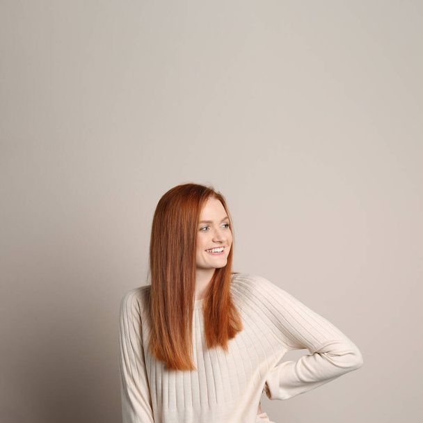Candid portrait of happy young woman with charming smile and gorgeous red hair on beige background - Foto, Bild