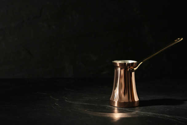 Beautiful copper turkish coffee pot on black table. Space for text - Zdjęcie, obraz