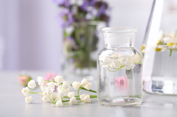 Laboratory glassware with different flowers on light table. Essential oil extraction - Foto, Imagem