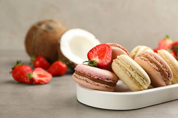 Delicious macarons, strawberries and coconut on grey table - Photo, Image
