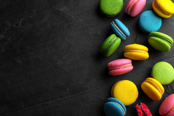Delicious colorful macarons on black table, flat lay. Space for text - Photo, image