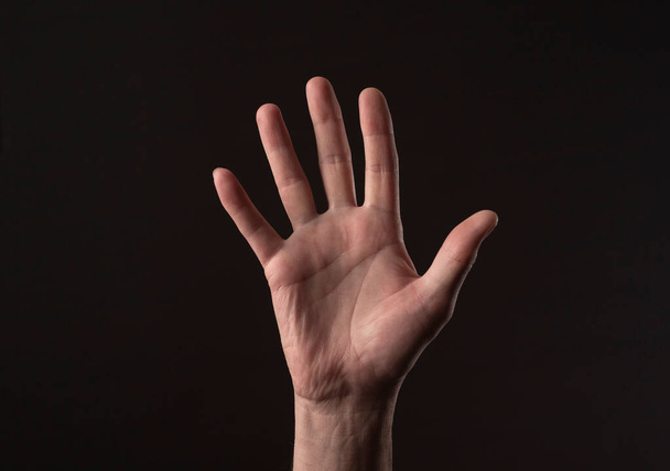 Male hand palm gesturing hello or hi over black background. greeting gesture - Photo, image