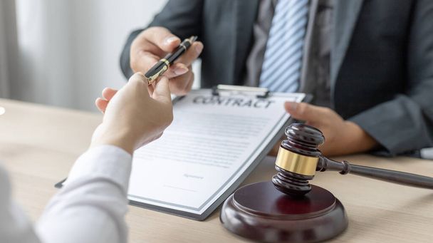 Attorney or lawyer handing client a pen to sign a business contract, Signing the contract according to the terms and conditions, scales of justice, law hammer, Concept of litigation and legal services - Photo, Image