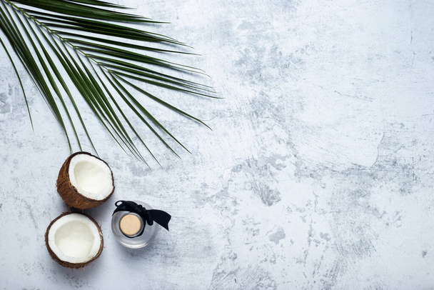 Opened coconut, bottle and palm leaf on concrete background. Top view, flat lay. - Foto, immagini